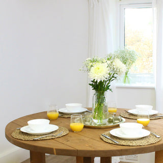 The Dalstan round dining table, a solid wood centerpiece exuding modern rustic charm. This bespoke farmhouse table offers customizable dimensions, style, color, and finish, ensuring a perfect fit for your Cottage or modern farmhouse kitchen.