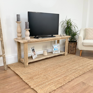 A console stand crafted from reclaimed wood. This television stand boasts a natural, distressed look, showcasing the beauty of salvaged wood. With its open shelf design, it's perfect for larger audio equipment and complements both cottage and Scandinavian decor styles