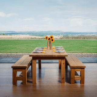 Hutton handmade rustic dining table in a warm Medium Oak finish, featuring chunky solid wood legs and a smooth, natural grain tabletop — ideal for a cosy kitchen or dining room
