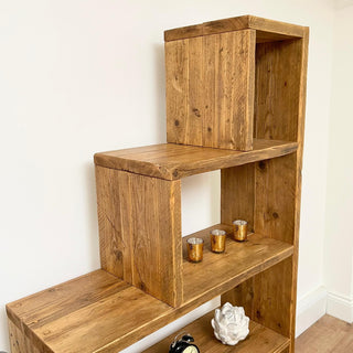 The Ashurst Reclaimed Bookcase offers versatile storage solutions for your home, featuring under stair shelves perfect for maximizing space. Crafted from reclaimed wood, this rustic shelving unit adds modern charm to any room, whether it's the living room, bedroom, hallway, or kitchen.