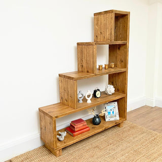 The Ashurst Reclaimed Bookcase offers versatile storage solutions with its under stair shelves, perfect for maximizing space in your home. This modern shelving unit features open compartments crafted from reclaimed wood, ideal for organizing books, shoes, or decor items.