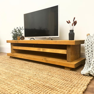Elevate your living room with the Ashlett TV unit, a handmade rustic entertainment unit designed to add style and functionality to your home. Crafted from solid wood, this console unit features a shelf for storage.