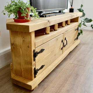 Experience rustic charm with the Hale TV unit, a handmade corner TV cabinet crafted from solid wood in Hampshire. The corner view showcases storage with rustic wooden doors.