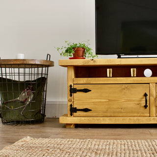 Discover the rustic charm of the Hale TV unit, a solid wood corner cabinet with natural knots and grain. Featuring rustic wooden doors and a soundbar shelf.