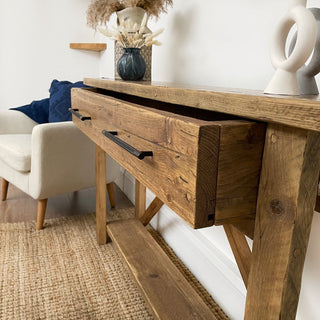 The Barton Console Unit, delivered fully assembled, offers a functional drawer for extra hallway storage. Crafted from chunky solid wood with a rustic design, this console table adds character to your home decor. Made from reclaimed wood, it serves as an ideal hallway table.